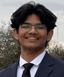 Young man with dark hair and glasses, wearing a dark suit and white shirt.